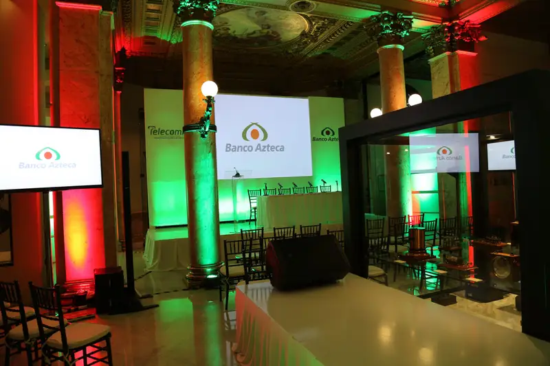 Salón corporativo con iluminación en rojo y verde y pantallas laterales