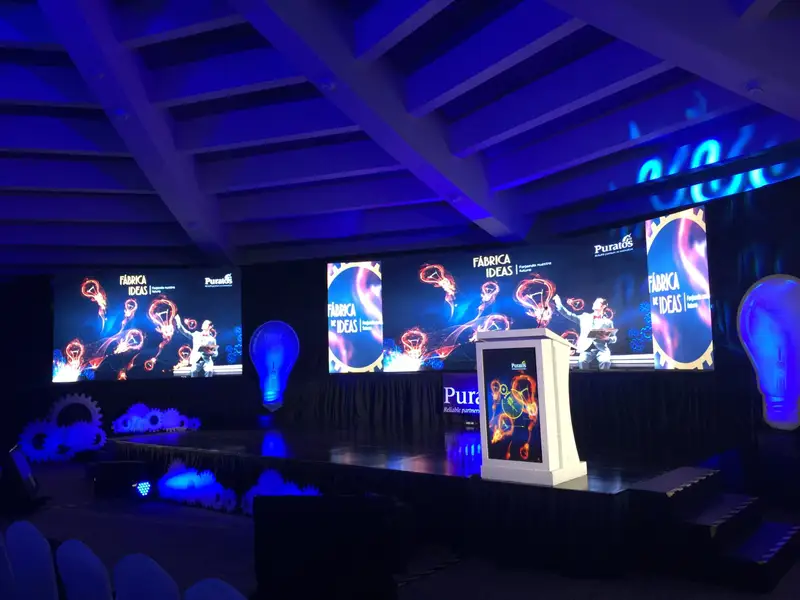 Escenario con pantallas LED, atril y elementos escenográficos iluminados en azul