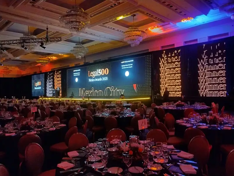 Salón de gala con mesas montadas, pantallas LED y paneles iluminados