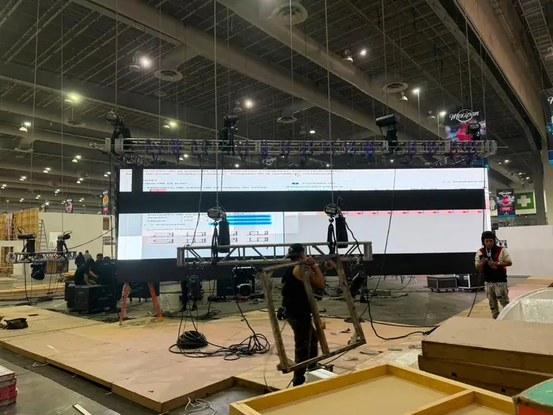 Técnicos montando un muro LED de gran formato con estructura colgada en un recinto de exposiciones