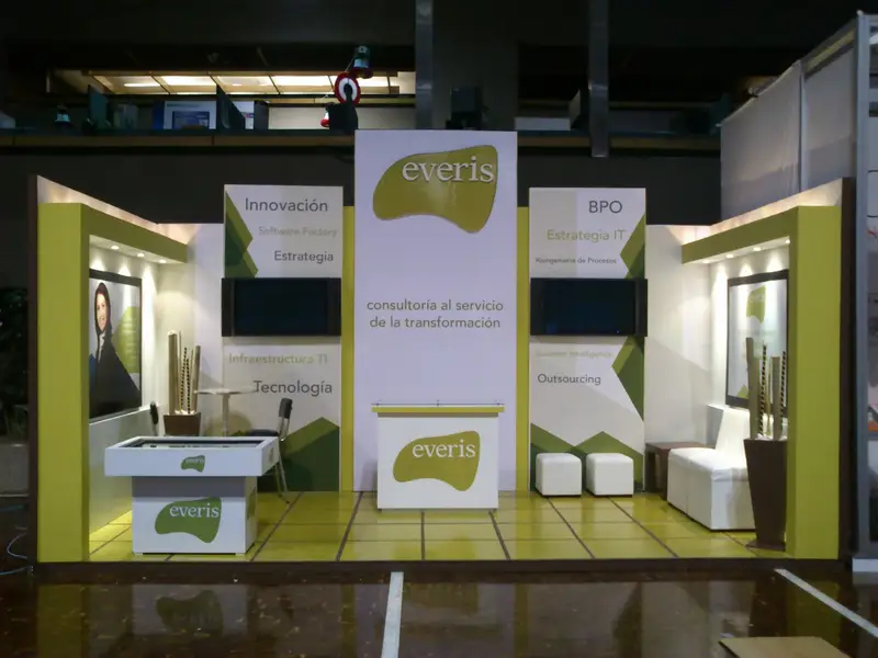 Stand corporativo con muros verdes y blancos, pantallas y mostradores